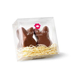 two chocolate covered caramel bunnies in a gift box with Easter grass